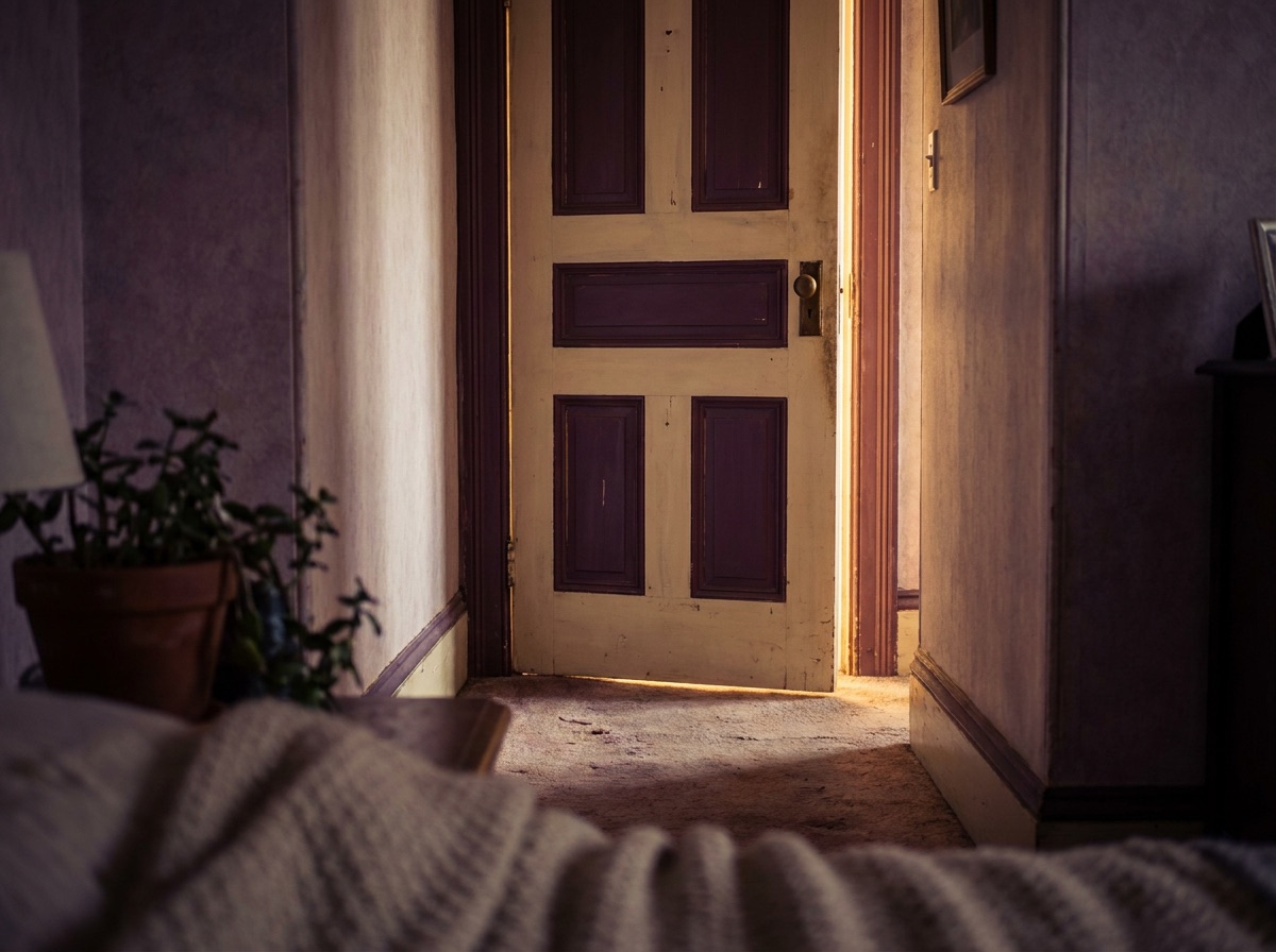 A wooden door with warm light glowing through the gap